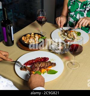 Couple au dîner en train de manger un steak, des fruits de mer avec du vin Banque D'Images