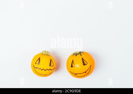 Citrouilles d'Halloween avec visages drôles heureux sur fond blanc, couché à plat. Banque D'Images