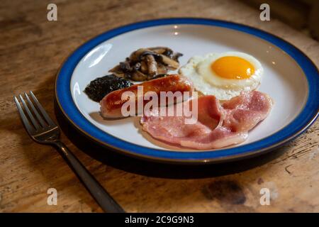 Assiette avec petit déjeuner cuisiné gallois complet composé d'œufs, saucisse, bacon, champignons et pain de lave Banque D'Images