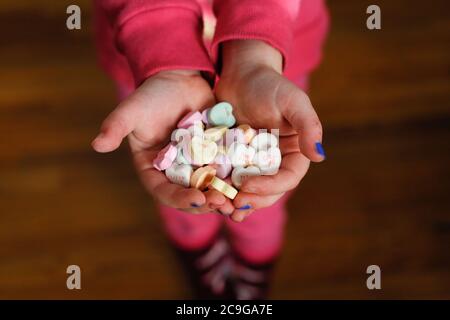 Les mains des enfants tiennent des coeurs de bonbons le jour de la Saint-Valentin Banque D'Images