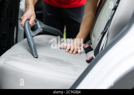 homme nettoyant intérieur de voiture sièges alcantara avec aspirateur Banque D'Images