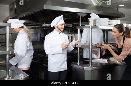 Personnel du restaurant avec jeune chef cuisinier travaillant ensemble dans la cuisine Banque D'Images