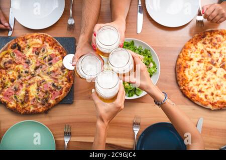 Vue de dessus de jeunes amis en dégustant de la bière et en dégustant une pizza sur le balcon. Concept d'été avec Buddies Drinking and Eating Banque D'Images