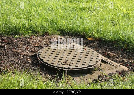 Couvercle de trou d'homme circulaire entouré d'herbe Banque D'Images