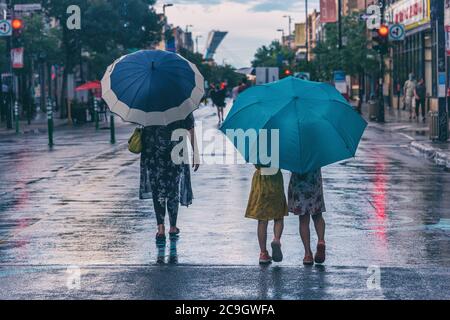 Montréal, CA - 30 juillet 2020 : mère et fille sur l'avenue Mont-Royal tenant des parasols sous la pluie et la tempête Banque D'Images