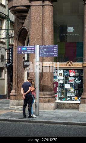 Un jeune couple touristique à côté d'un panneau d'accès au centre-ville à Liverpool Banque D'Images