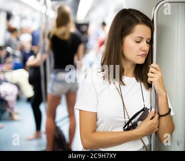 Portrait de jeune femme fatiguée avec les yeux fermés en voiture de métro tenir debout sur la rampe Banque D'Images