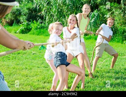 Les enfants ayant des mères et pères jouer remorqueur de la guerre durant les jeux en plein air aux beaux jours Banque D'Images