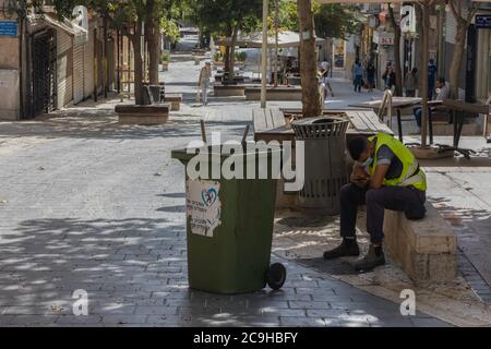 Jérusalem, Israël - 30 juillet 2020: Un nettoyeur de rue assis sans rien sur Ben - Yehuda centre commercial piétonnier, habituellement une rue principale bondée de Jérusalem, presque Banque D'Images