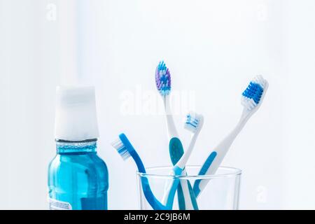 Brosses à dents en verre avec bain de bouche sur fond simple. Banque D'Images