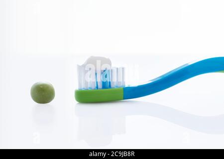Brosse à dents avec une quantité de dentifrice de la taille d'un pois sur fond blanc. Banque D'Images
