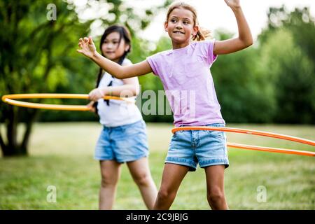 Filles jouant avec des hula Hoops dans le parc. Banque D'Images