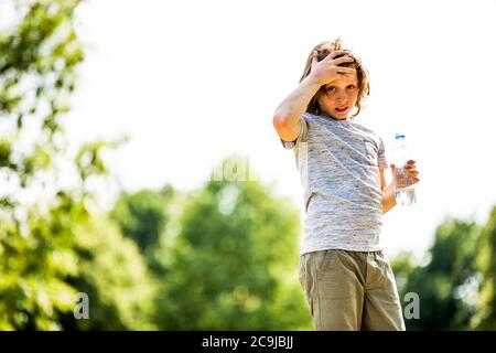 Garçon tenant une bouteille d'eau dans le parc, portrait. Banque D'Images