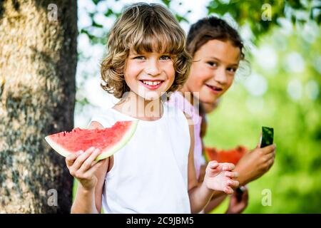 Enfants qui mangent de la pastèque dans le parc. Banque D'Images