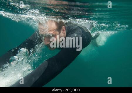 Image sous l'eau d'un jeune homme qui s'accélère à travers l'eau. Banque D'Images