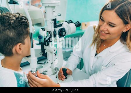 Ophtalmologiste examinant les yeux du garçon avec une lampe fendue . Banque D'Images