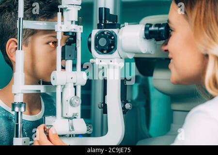 Ophtalmologiste examinant les yeux du garçon avec une lampe fendue . Banque D'Images