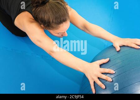Exercice de flexibilité dans le bas du dos, jeune femme s'entraîner avec un ballon de fitness. Banque D'Images