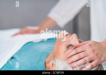 Marma praticien de thérapie équilibrant la tête du patient et l'estomac chakras. Banque D'Images