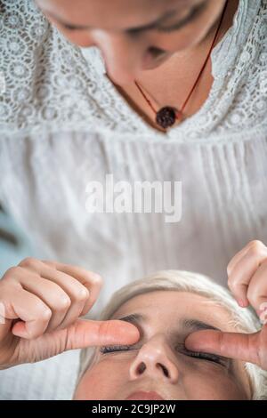 Marma thérapie. Femme sénichée sur une table de massage et bénéficiant d'un traitement oculaire Ayurveda (Urdhaw et Adhoakshi). Banque D'Images