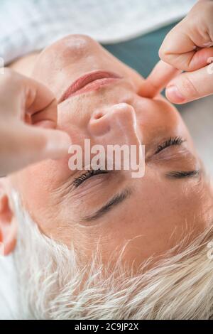 Marma thérapie. Femme sénichée sur une table de massage et bénéficiant d'un soin du visage Ayurveda. Banque D'Images