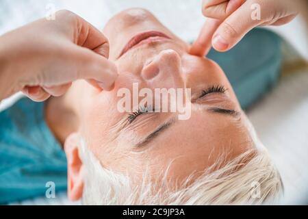 Marma thérapie. Femme sénichée sur une table de massage et bénéficiant d'un soin du visage Ayurveda. Banque D'Images