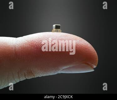 Microchip du bout des doigts. Doigt tenant une micropuce miniaturisée. Banque D'Images