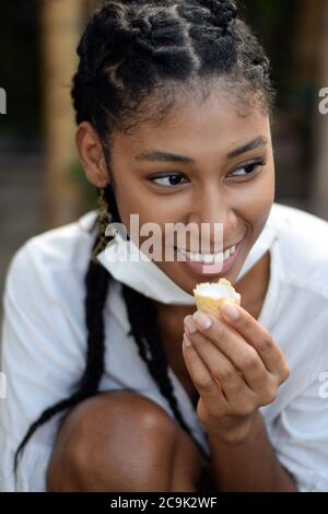 Jeune femme mangeant une crème glacée avec un masque facial autour de son menton à Bogota, Colombie, pendant l'épidémie de 2019-20 du nouveau coronavirus SRAS-COV-2. Banque D'Images