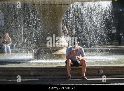 Francfort, Allemagne. 31 juillet 2020. Un homme mange une glace à côté d'une fontaine près d'Alte Oper à Francfort, en Allemagne, le 31 juillet 2020. La température la plus élevée de Francfort a atteint 35 degrés Celsius vendredi. Crédit: Lu Yang/Xinhua/Alay Live News Banque D'Images