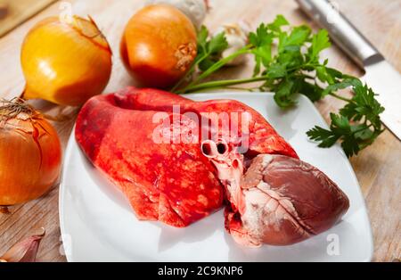 Cœur d'agneau frais et poumons sur planche à découper en bois avec assaisonnements. Cuisine maison Banque D'Images