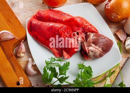 Image de poumons d'agneau crus et de coeur servi avec des légumes verts pendant la cuisson Banque D'Images