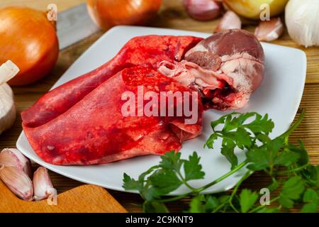 Image de poumons d'agneau crus et de coeur servi avec des légumes verts pendant la cuisson Banque D'Images