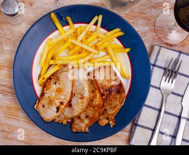 Délicieux déjeuner copieux composé de steaks de porc rôti servi avec des pommes de terre frites Banque D'Images