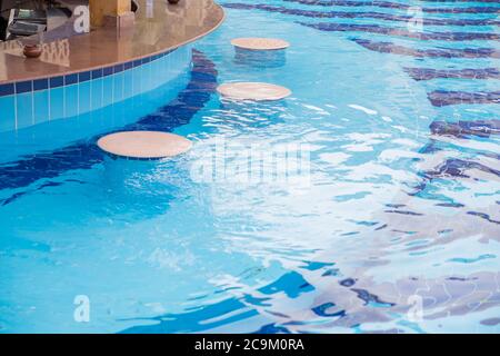 comptoir de bar dans la piscine avec eau claire et chaises Banque D'Images