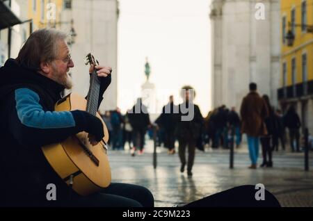 LISBONNE, PORTUGAL - 3 FÉVRIER 2019 : portait sombre moody d'un ancien interprète de rue jouant de la guitare en hiver sur Rua Augusta, rue commerçante principale o Banque D'Images