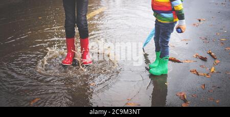 La marche de l'enfant dans la flaque en wellies sur temps de pluie Banque D'Images