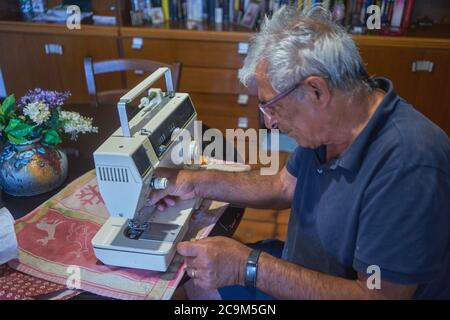 homme âgé utilisant une machine à coudre Banque D'Images