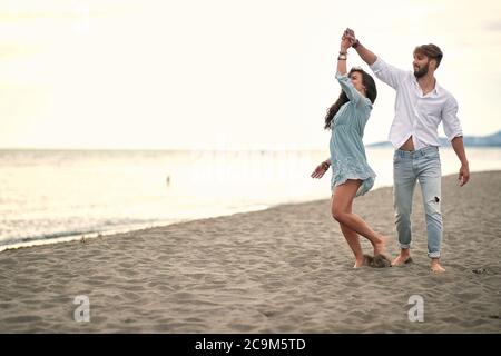 Couple heureux romantique danse au bord de la mer à la plage. Banque D'Images