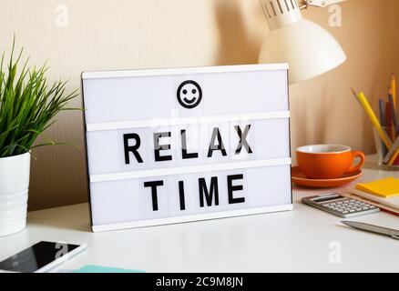 Détendez-vous en termes de temps et d'équilibre de travail grâce au texte sur la boîte lumineuse sur la table de bureau dans le bureau à domicile.émotion positive au succès.corps sain Banque D'Images