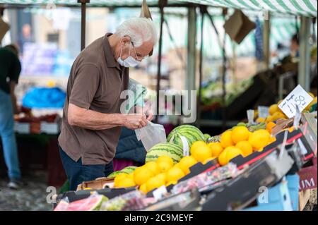 Richmond, North Yorkshire, Royaume-Uni - 1er août 2020 : un homme âgé portant un masque facial protecteur dans un marché de fruits et légumes en plein air Banque D'Images