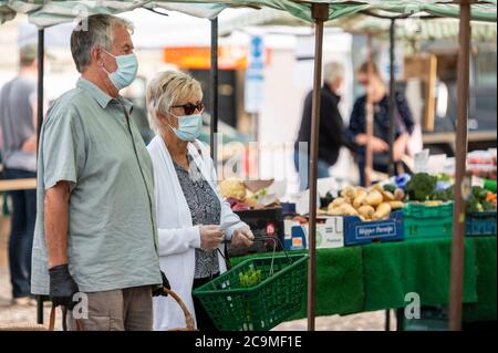 Richmond, North Yorkshire, Royaume-Uni - 1er août 2020 : un couple mature portant des masques protecteurs fait du shopping dans un marché aux fruits et légumes Banque D'Images