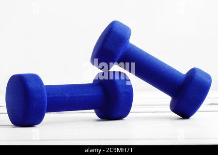 haltères poids pour la forme physique couleur bleue sur bois blanc. Banque D'Images