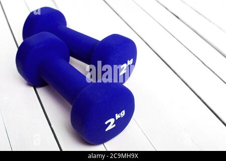 haltères poids pour la forme physique couleur bleue sur bois blanc. Banque D'Images
