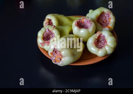 Portion de poivrons farcis crus sur une assiette en argile brune. Cuisson des poivrons farcis. Fait partie de la série. Plats faits maison. Mise au point sélective. Banque D'Images