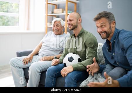 Les fans du sport de trois générations regardent le football à la télévision Banque D'Images