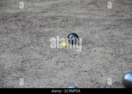 Boules de pétanque et petit jack jaune sur terrain de pétanque, Banque D'Images