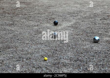 Boules de pétanque et petit jack jaune sur terrain de pétanque, Banque D'Images