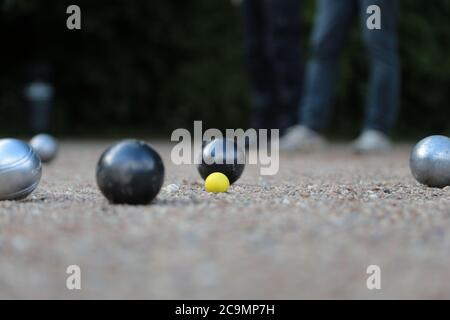 Boules de pétanque et petit jack jaune sur terrain de pétanque, Banque D'Images