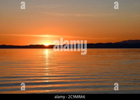 Vue panoramique sur le lac de Garde avec la côte en arrière-plan au coucher du soleil, Bardolino, Vérone, Vénétie, Italie Banque D'Images