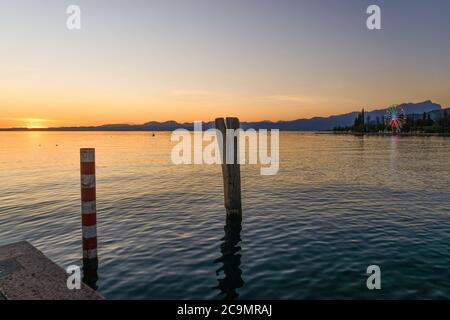 Vue panoramique sur le lac de Garde depuis une jetée avec la côte montagneuse en arrière-plan au coucher du soleil, Bardolino, Vérone, Vénétie, Italie Banque D'Images